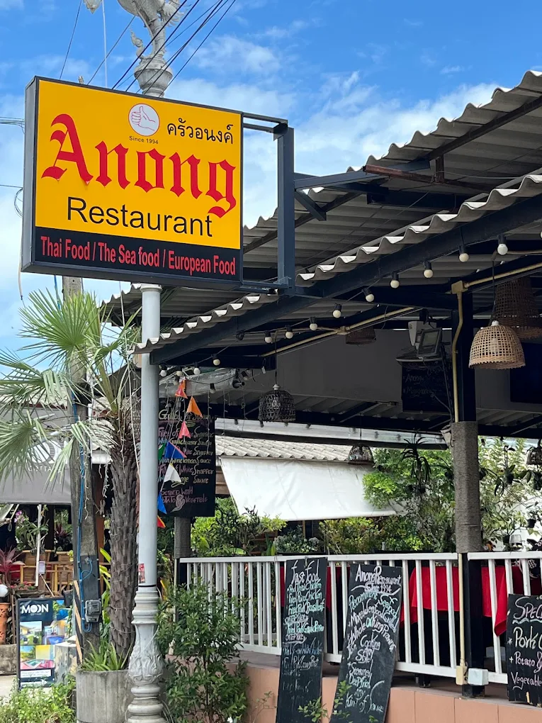 The original yellow Anong Restaurant sign with red lettering and the Thai name ครัวอนงค์, Since 1994, above the open-fronted restaurant in Choeng Mon